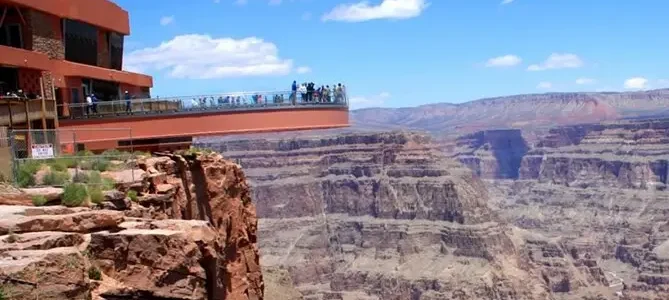 Visitors on the glass Skywalk extending over the Grand Canyon with panoramic views of the canyon walls and valley below.