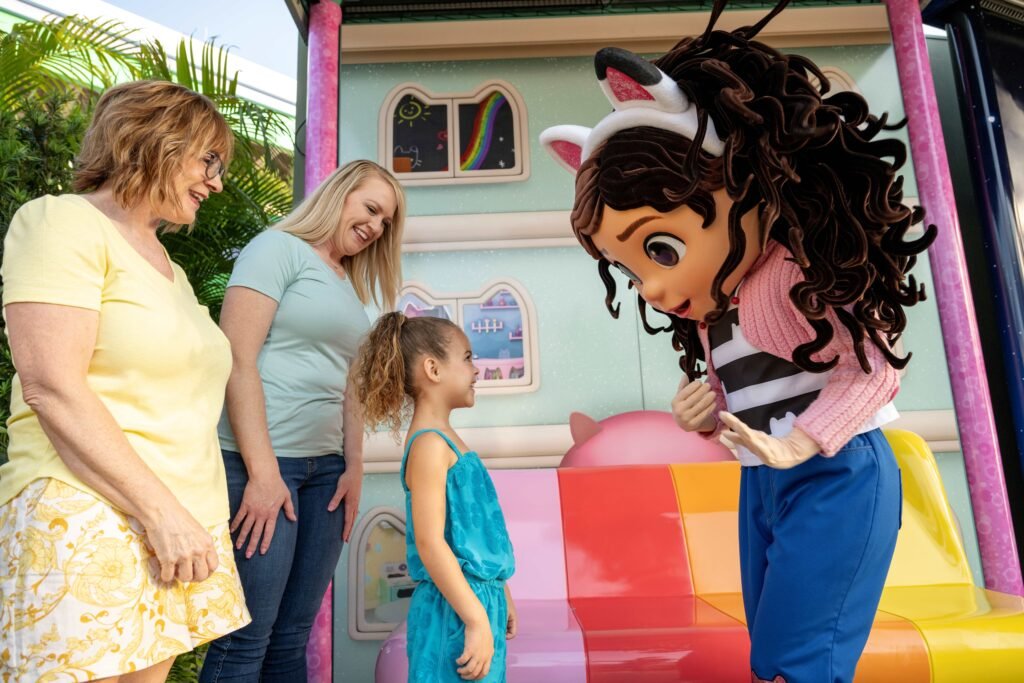 Visitors interacting with a character from Gabby’s Dollhouse near a colorful play structure at Universal Studios.