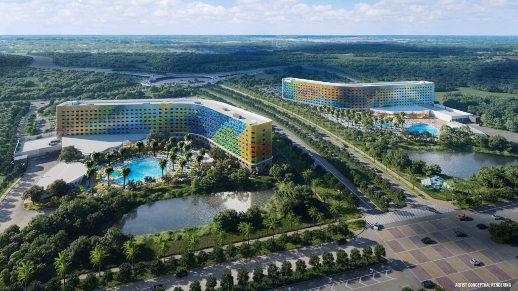 Aerial view of Universal Studios resort with colorful buildings surrounded by lush greenery and a large pool area.