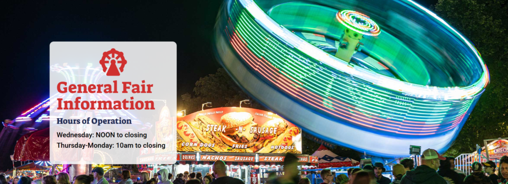 “Nighttime view of a spinning carnival ride at Columbia County Fair with bright lights in motion against a dark sky. In the background, other attractions and stands are lit up with people around them.