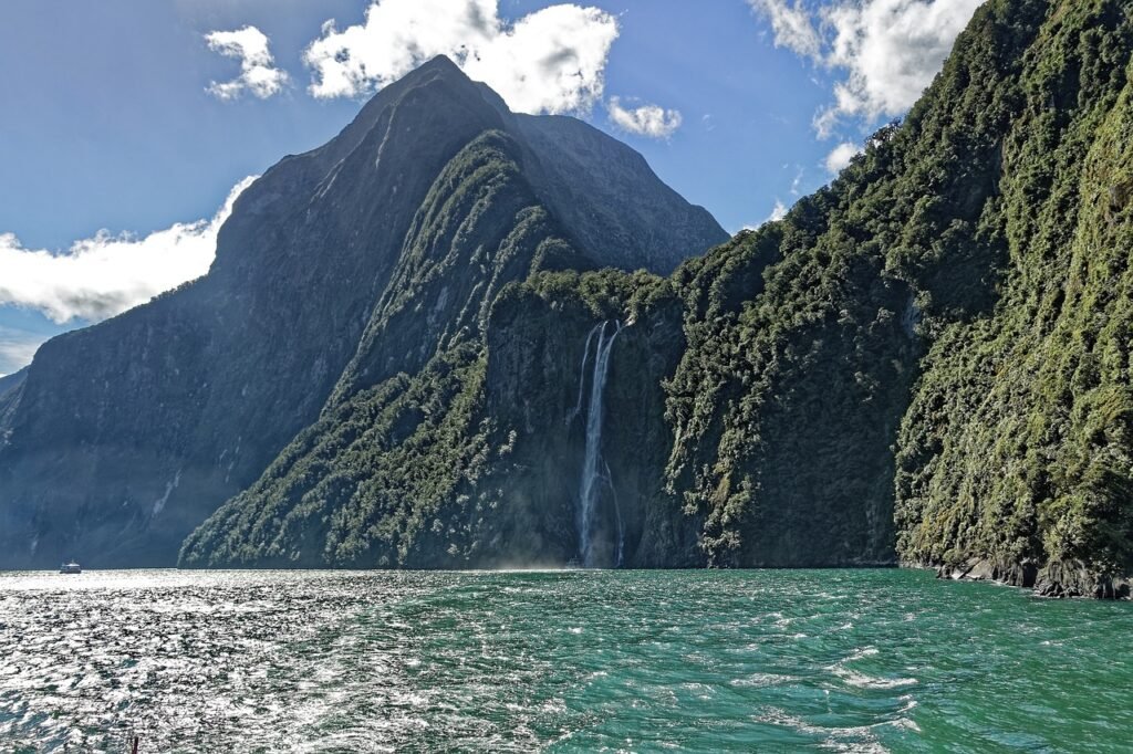 Milford Sound, New Zealand - Serene landscape with a body of water surrounded by lush greenery and towering mountains.