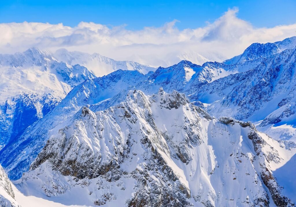 Snow-covered peaks of the Swiss Alps under a clear blue sky, showcasing Switzerland’s rugged mountain terrain.