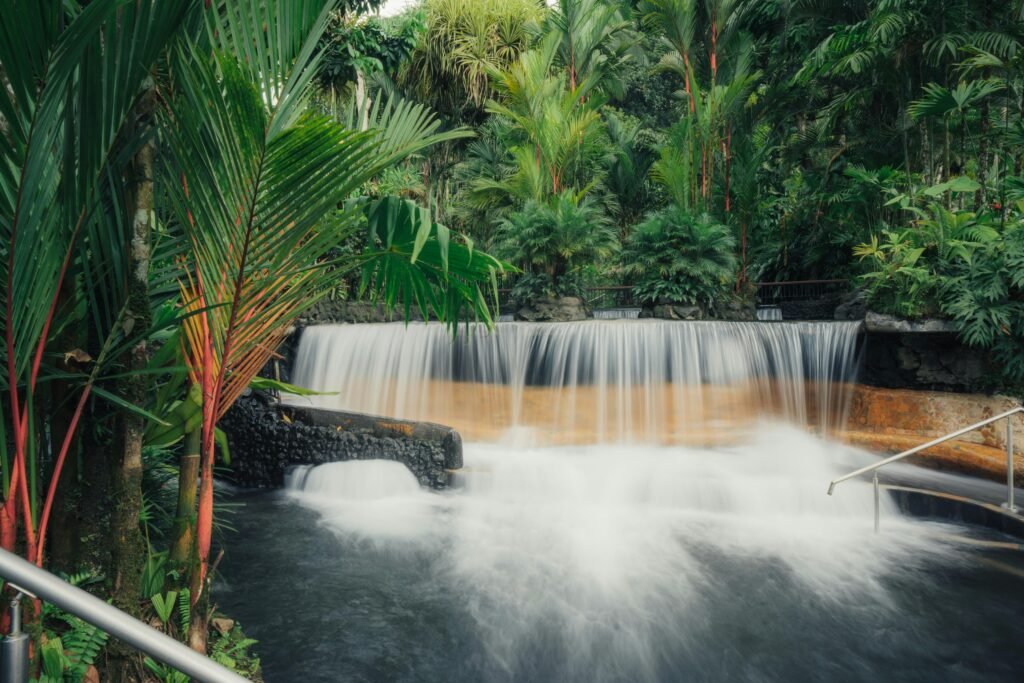 A serene waterfall cascades into a misty pool surrounded by lush tropical vegetation in Costa Rica.