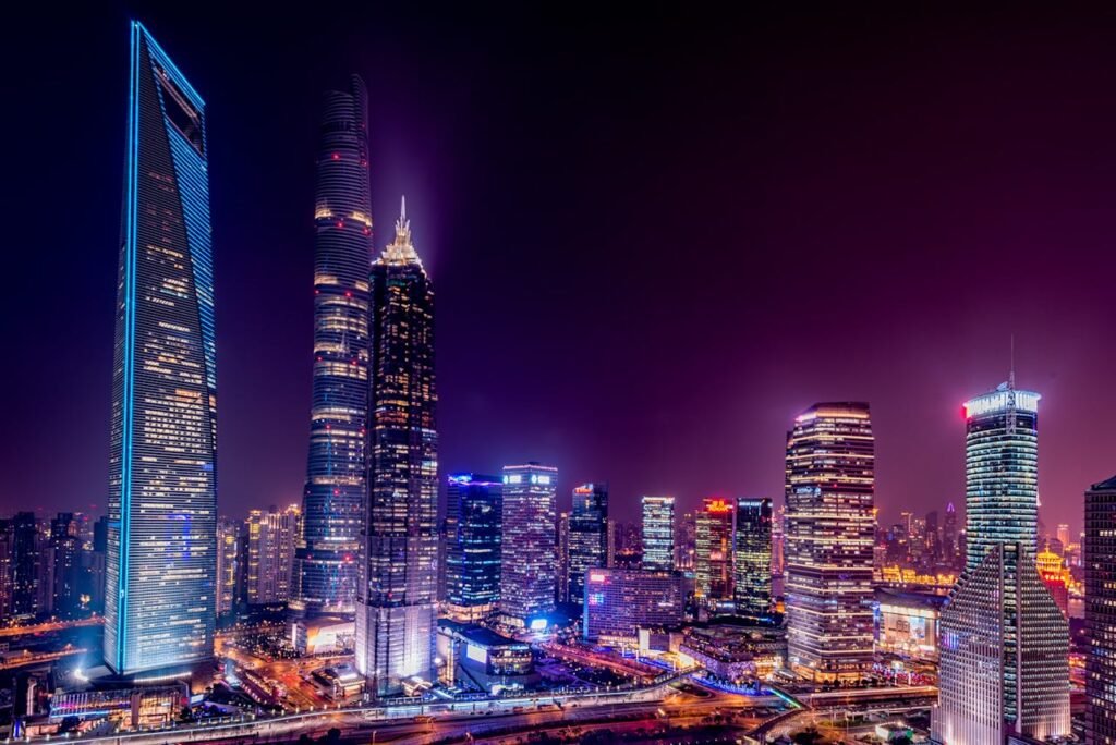 A nighttime cityscape showcasing a cluster of illuminated skyscrapers against a twilight sky.