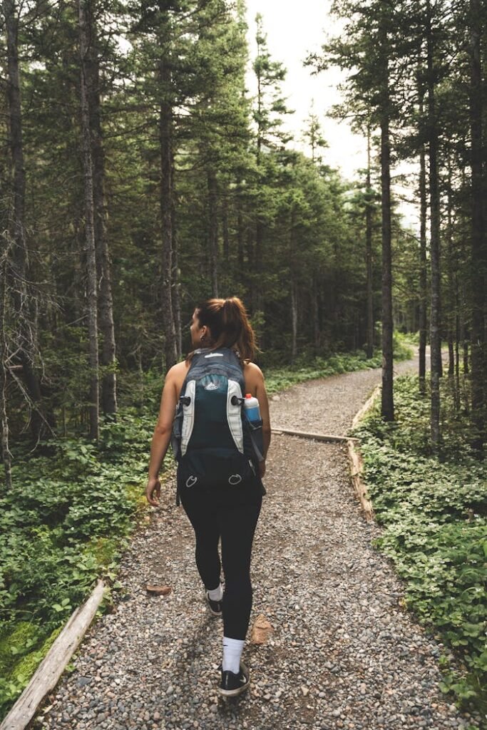 A person with a backpack walking on a forest trail, with their face obscured by pixelation. Labor Day travel tips