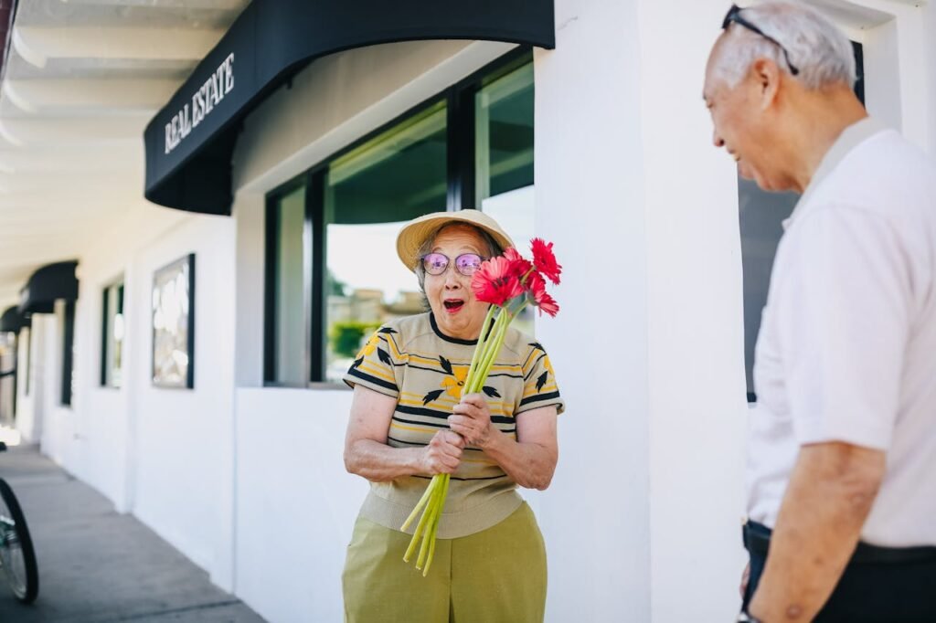 Happy woman holding red flowers her husband surprised her with, smiling in front of a building.