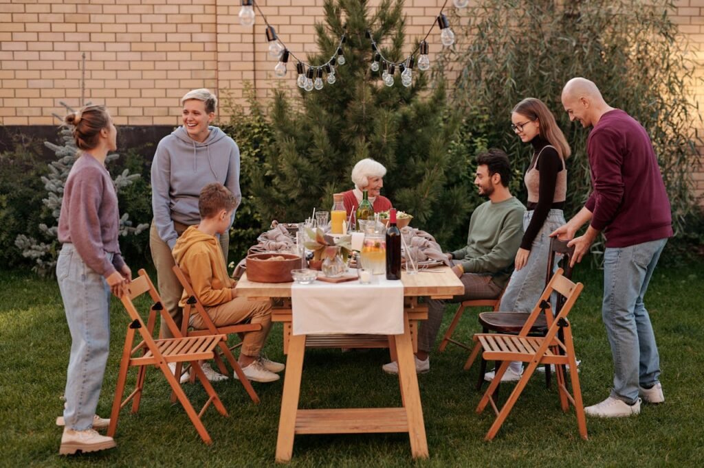 A group of people enjoying an outdoor meal together at a wooden table set with various dishes. Labor Day Travel Tip: Be Present with others