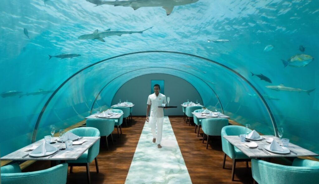 Underwater restaurant with a transparent tunnel-like ceiling showcasing marine life at Conrad Maldives.