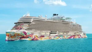 Norwegian Aqua cruise ship with multiple decks and vibrant mural, sailing on the ocean.