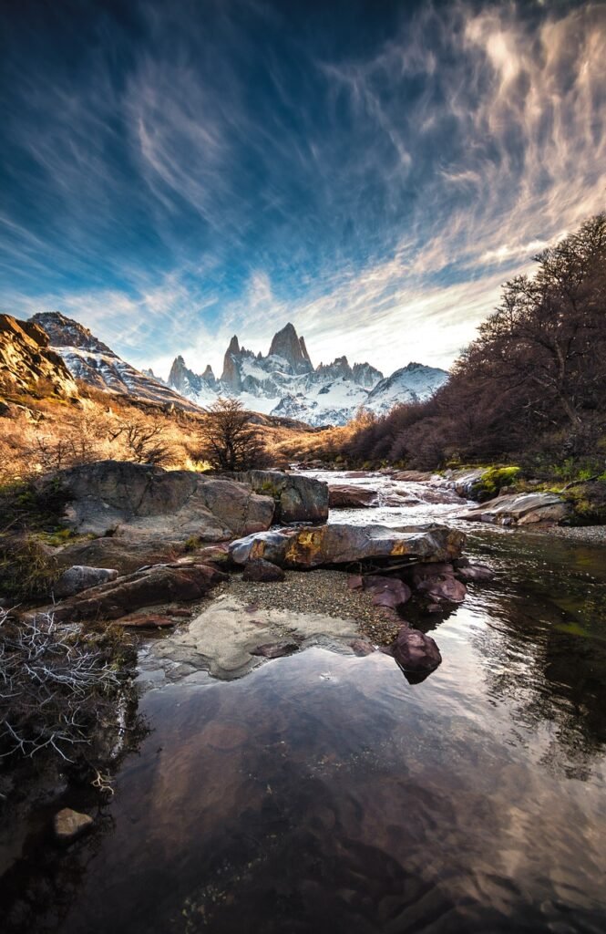 Scenic view of Patagonia with rugged mountain peaks, river, and dramatic sky. Trending Travel Destinations 2024