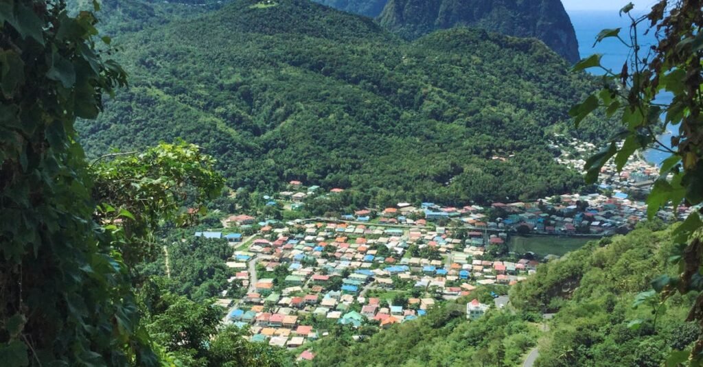 Aerial view of a small town in St. Lucia surrounded by lush green hills and colorful rooftops.