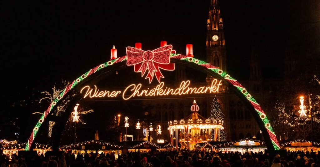 Illuminated archway entrance with ‘Wiener Christkindlmarkt’ sign at Vienna Christmas market, Austria, at night. 