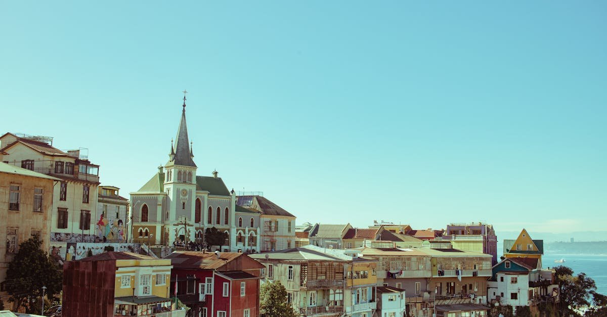 A panoramic view of Valparaíso showcasing its colorful buildings, the prominent spire of a church, and the Pacific Ocean in the background.