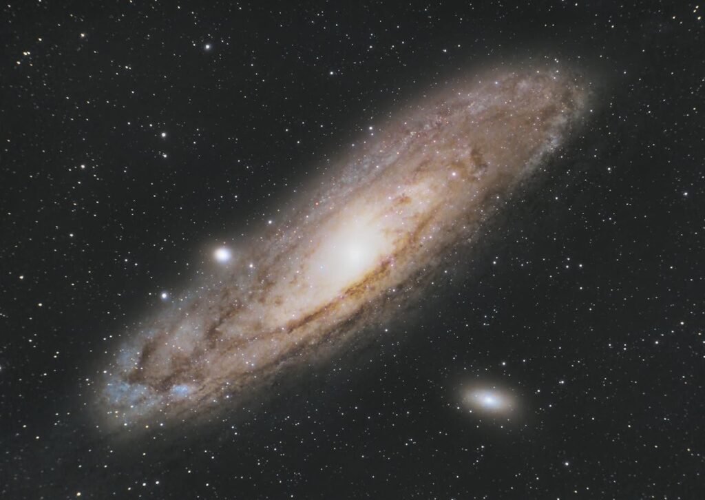 Image of the Andromeda Galaxy with its spiral arms and bright core against a starry night sky, accompanied by a smaller elliptical galaxy. September 2024 celestial events.