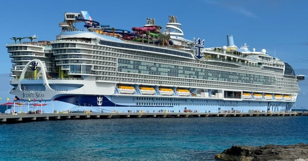 Royal Caribbean cruise ship docked in a clear blue water port with a rocky shoreline in the foreground. during a Caribbean and West Indies Vacation