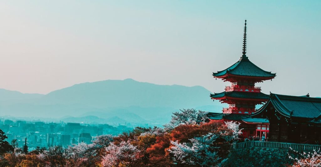 Red Japanese pagoda amidst cherry blossoms with a hazy city and mountain background.  Trending travel destinations 2024.