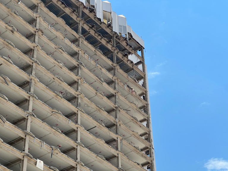 Exterior view of the Tropicana Las Vegas hotel’s tower with visible signs of disrepair and preparation for demolition under a clear blue sky.