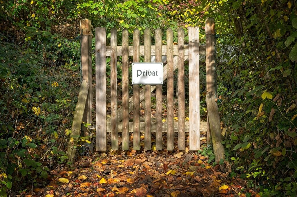 Wooden gate with a 'Privat' sign surrounded by dense foliage and autumn leaves showing Kindness and Boundaries