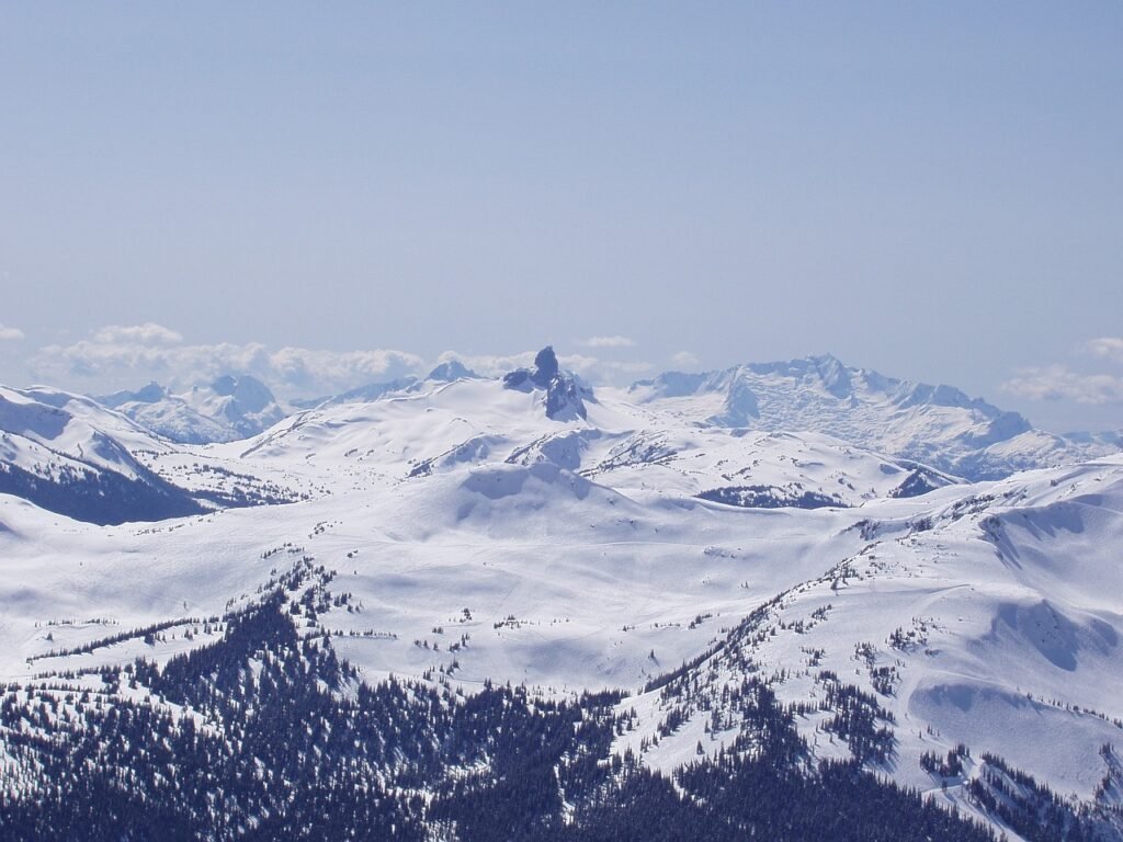 Snow-covered Whistler Blackcomb mountain range with a prominent peak under a clear blue sky