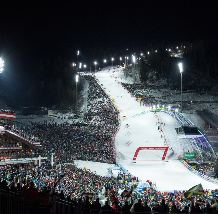 Nighttime ski austria race in Schladming with illuminated slopes and spectators.